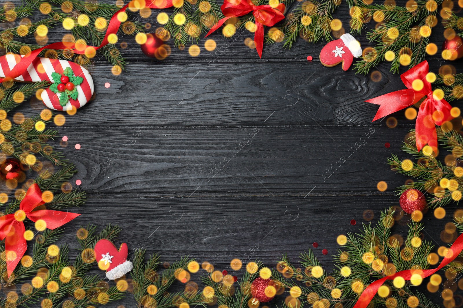 Photo of Christmas greeting card with space for text. Flat lay composition of fir tree branches and festive decor on black wooden background