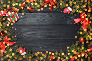 Christmas greeting card with space for text. Flat lay composition of fir tree branches and festive decor on black wooden background