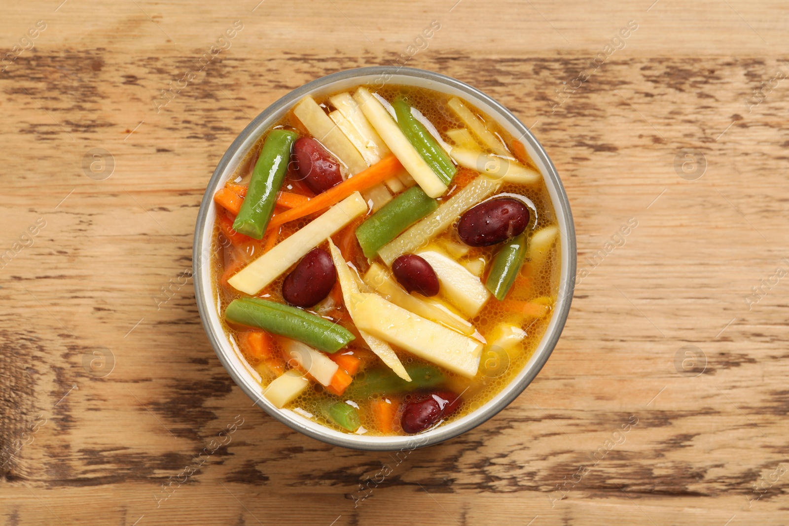 Photo of Bowl of delicious turnip soup on wooden table, top view