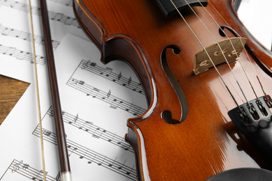 Beautiful violin, bow and note sheets on table, closeup