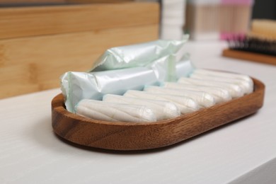 Photo of Wooden tray with many tampons on white table, closeup. Menstrual hygienic product