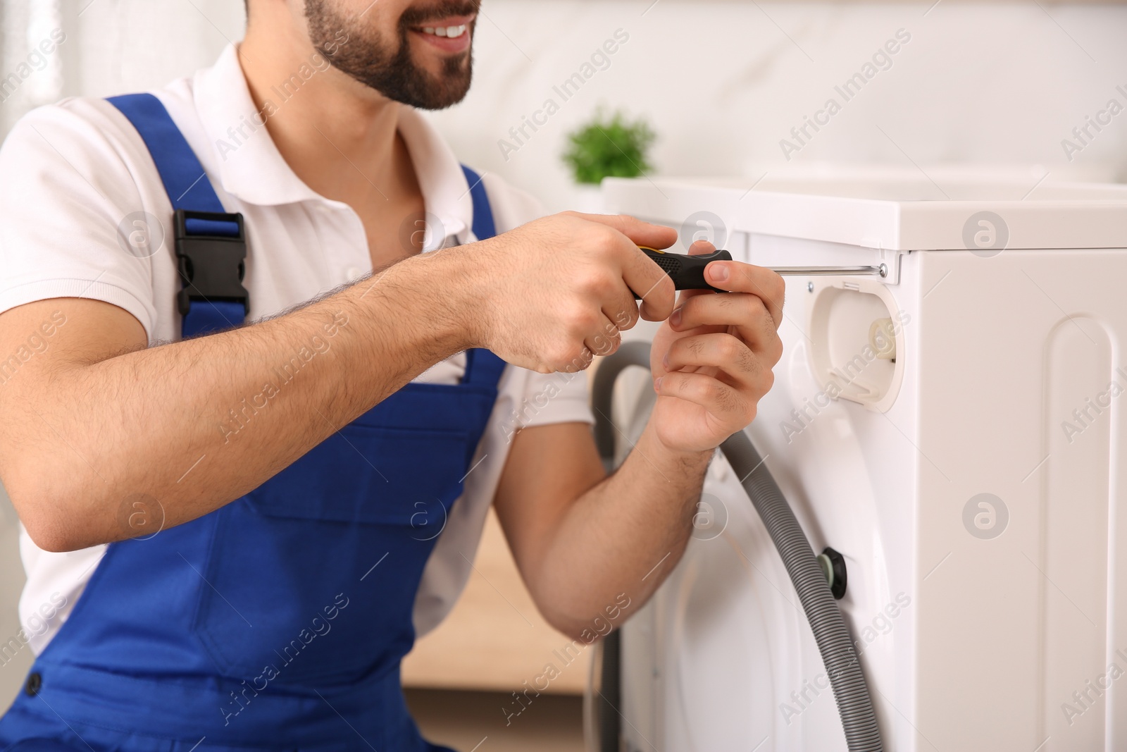 Photo of Professional plumber repairing washing machine in bathroom, closeup