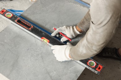 Photo of Worker measuring tiles for installation, closeup view