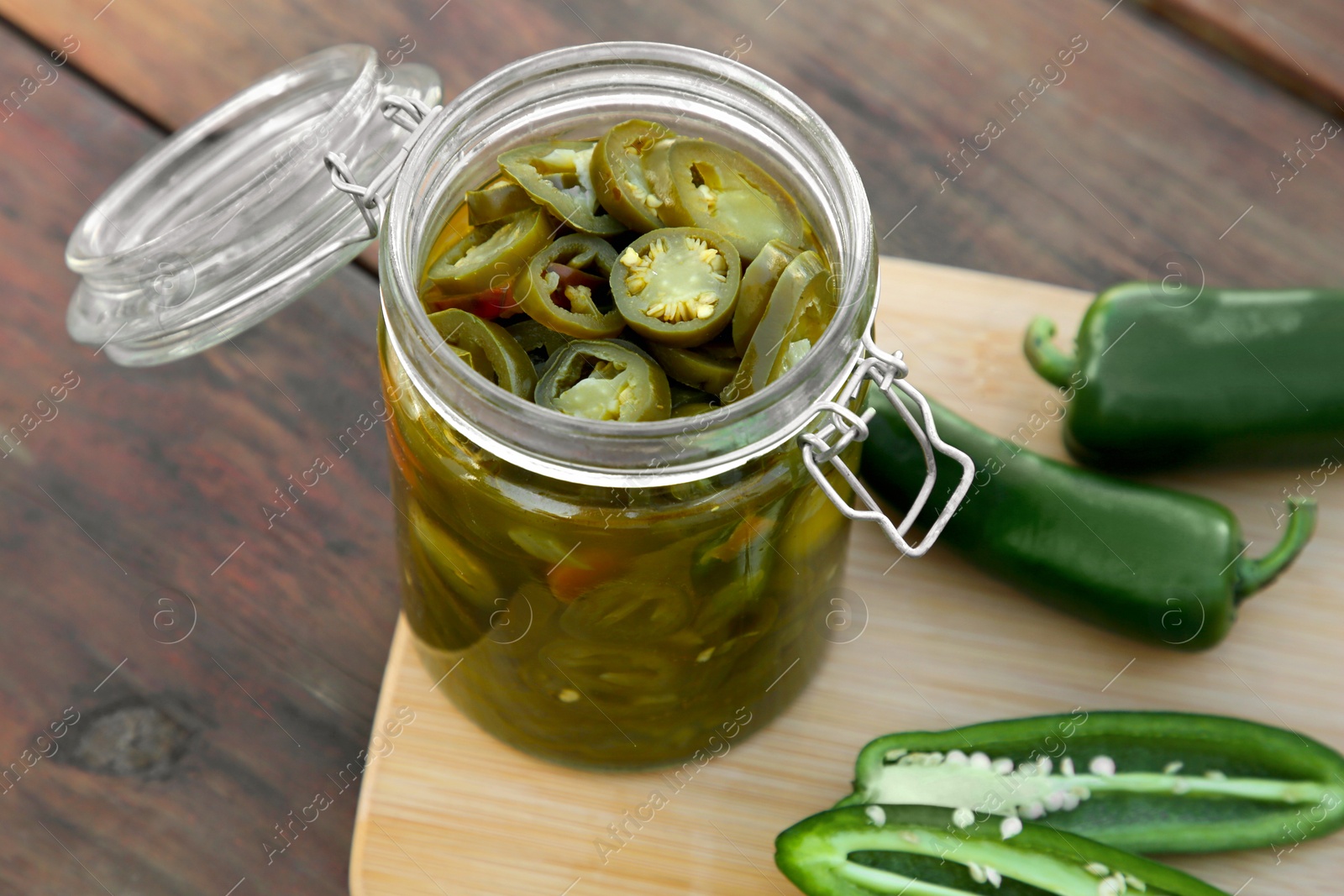 Photo of Fresh and pickled green jalapeno peppers on wooden table, closeup