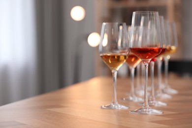 Photo of Different sorts of wine in glasses on wooden table indoors. Space for text