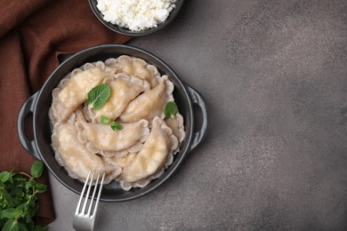 Delicious dumplings (varenyky) with cottage cheese and mint served on brown table, flat lay. Space for text