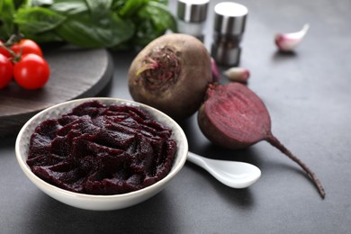 Photo of Bowl with tasty beet puree and ingredients on black table