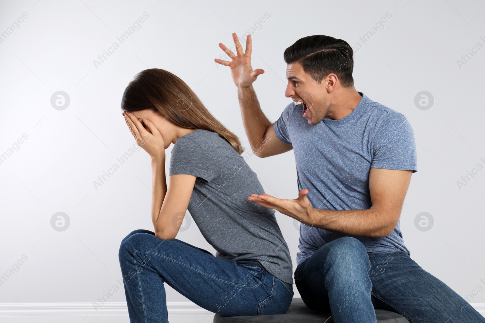 Photo of Man shouting at his girlfriend on light background. Relationship problems