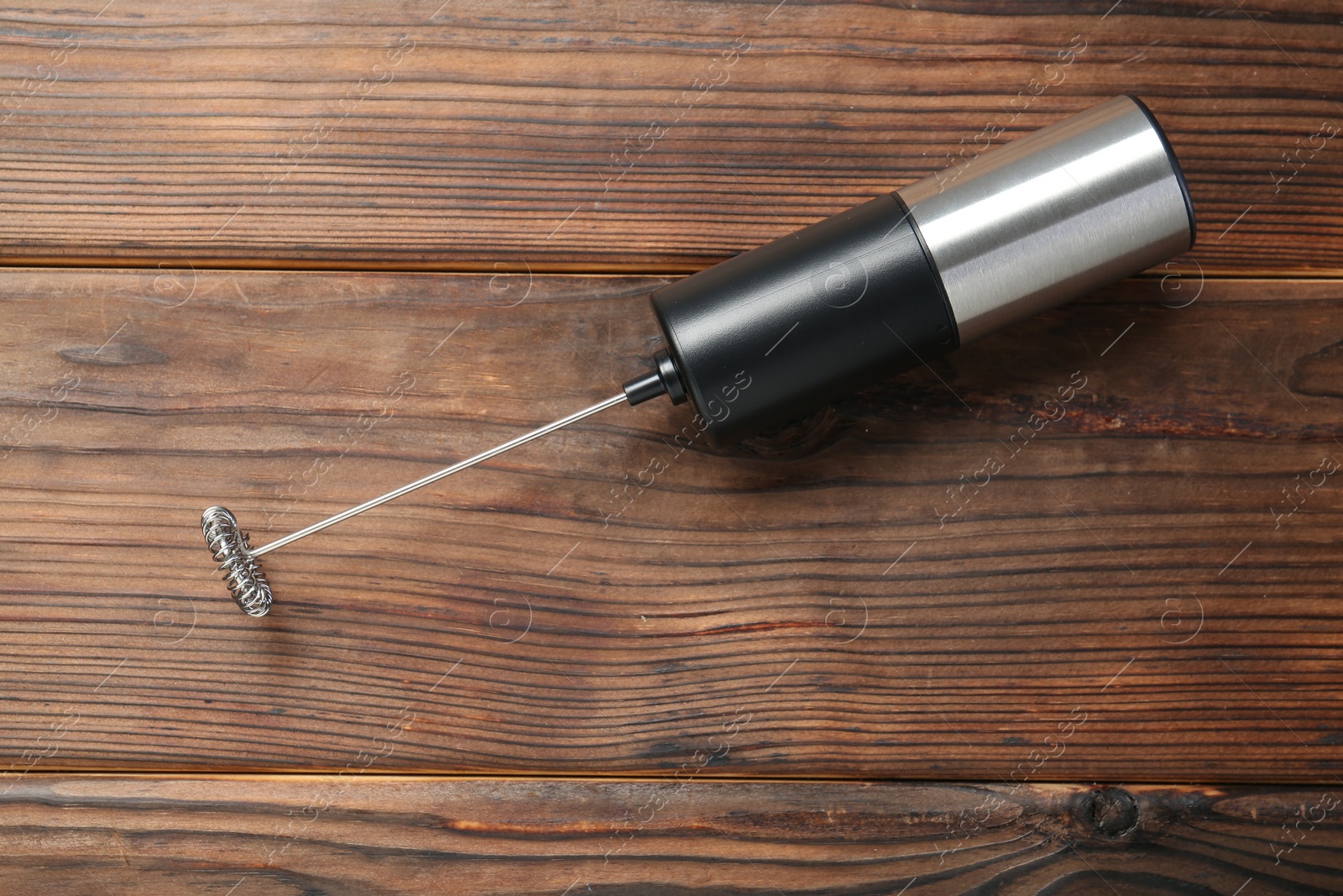 Photo of Black milk frother wand on wooden table, top view