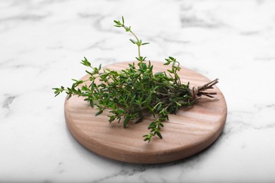 Board with aromatic fresh thyme on white marble table