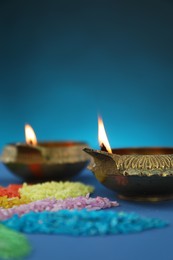 Photo of Diwali celebration. Diya lamps and colorful rangoli on blue background, closeup