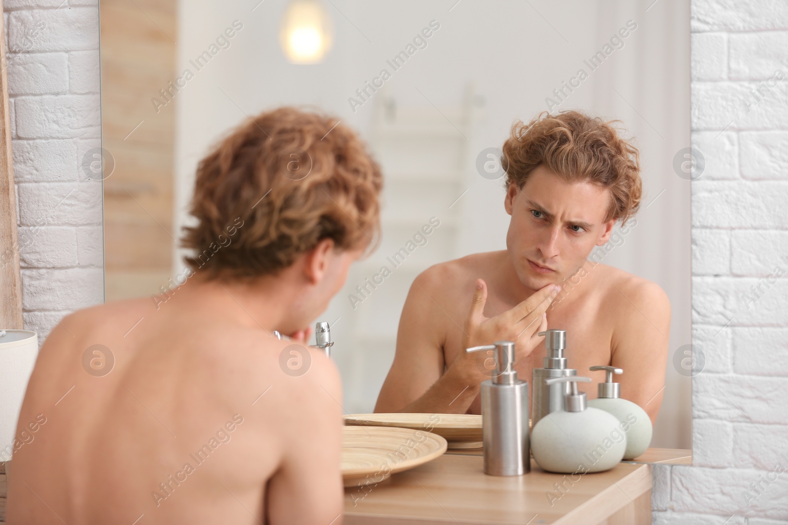 Photo of Young man looking in mirror after shaving at home