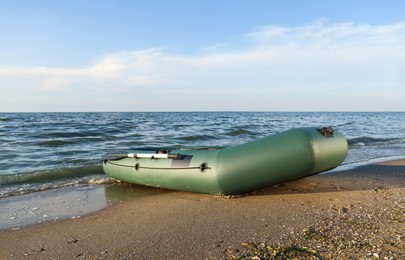 Inflatable rubber fishing boat on sandy beach near sea