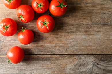 Photo of Fresh ripe tomatoes on wooden table, flat lay. Space for text