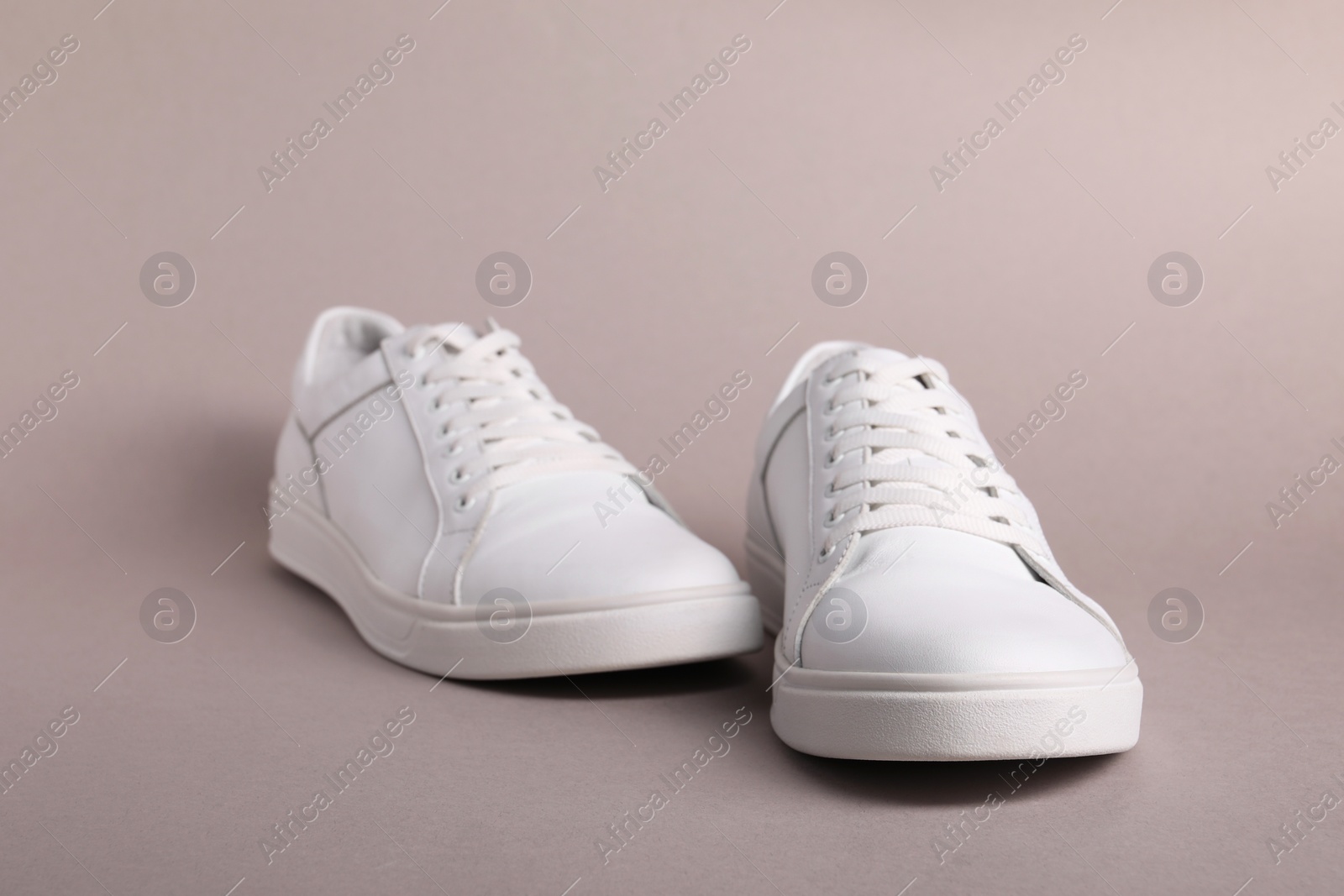 Photo of Pair of stylish white sneakers on grey background