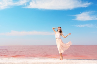 Beautiful woman posing near pink lake on sunny day