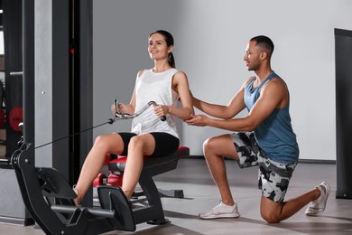 Photo of Trainer explaining woman how to do exercise properly in modern gym
