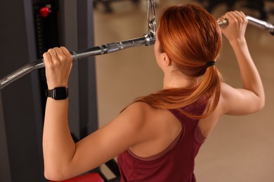 Photo of Young woman training in modern gym, back view