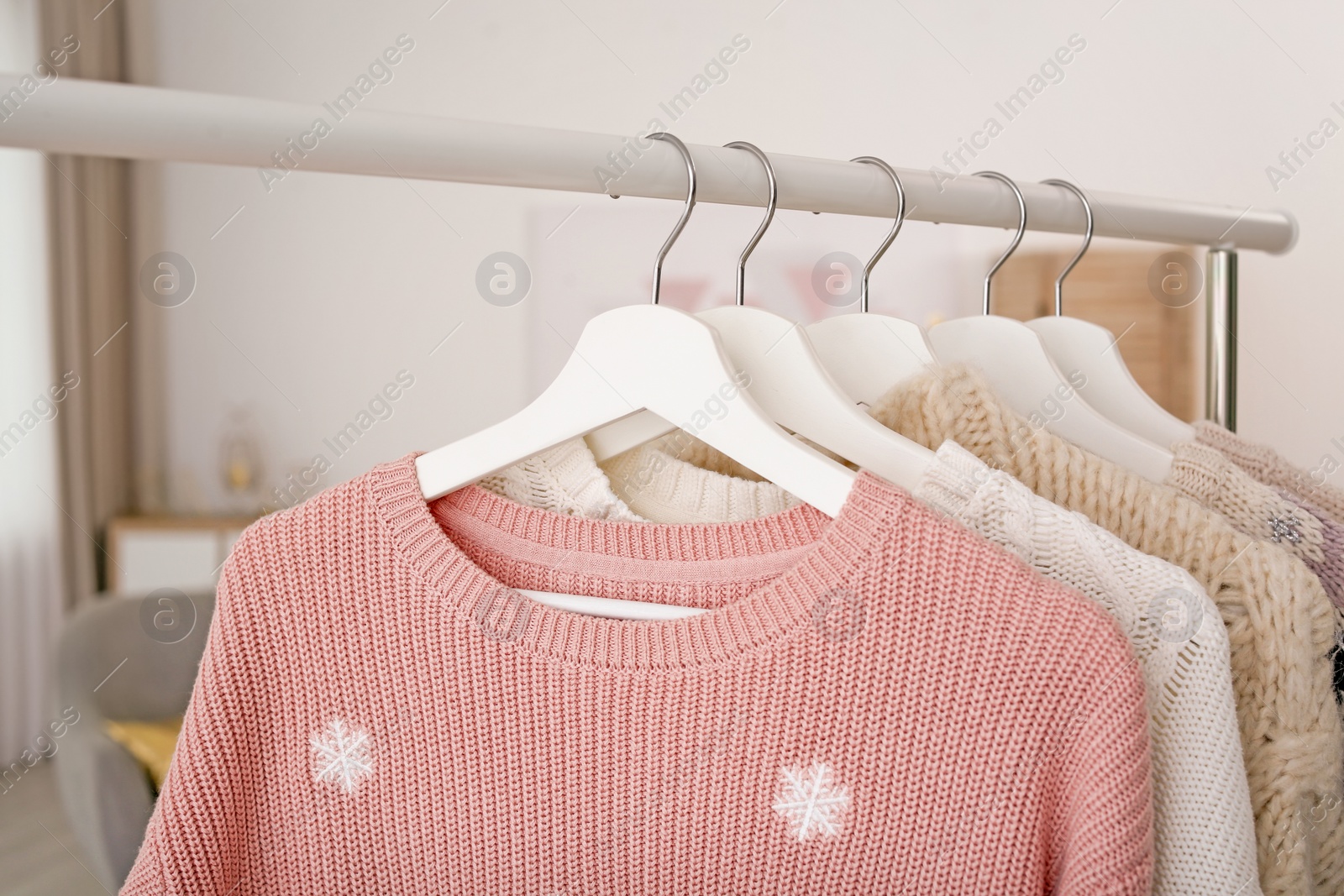 Photo of Wardrobe rack with warm clothes indoors, closeup