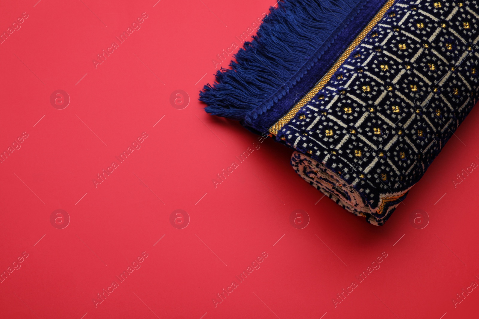 Photo of Muslim prayer rug on red background, top view. Space for text