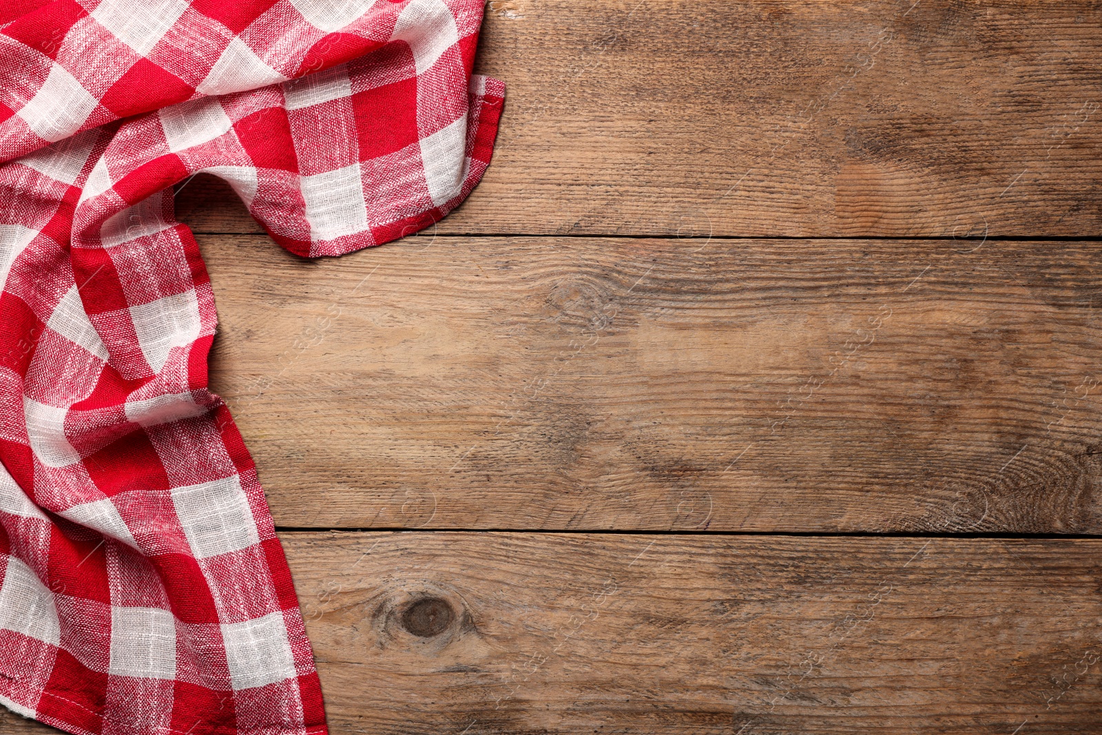 Photo of Checkered tablecloth on wooden table, top view. Space for text