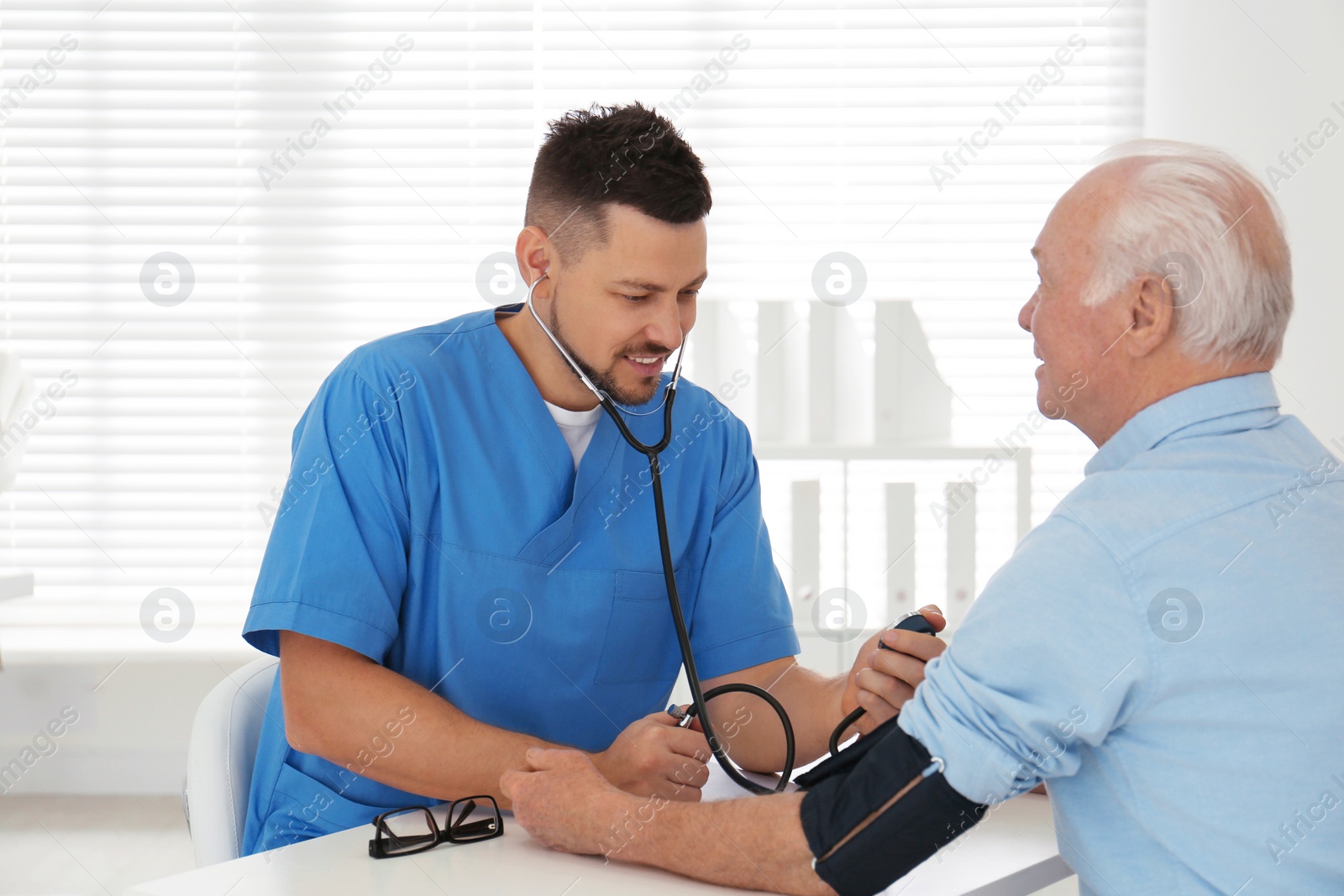 Photo of Doctor measuring blood pressure of senior patient in office