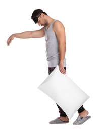 Man with pillow and eye mask in sleepwalking state on white background