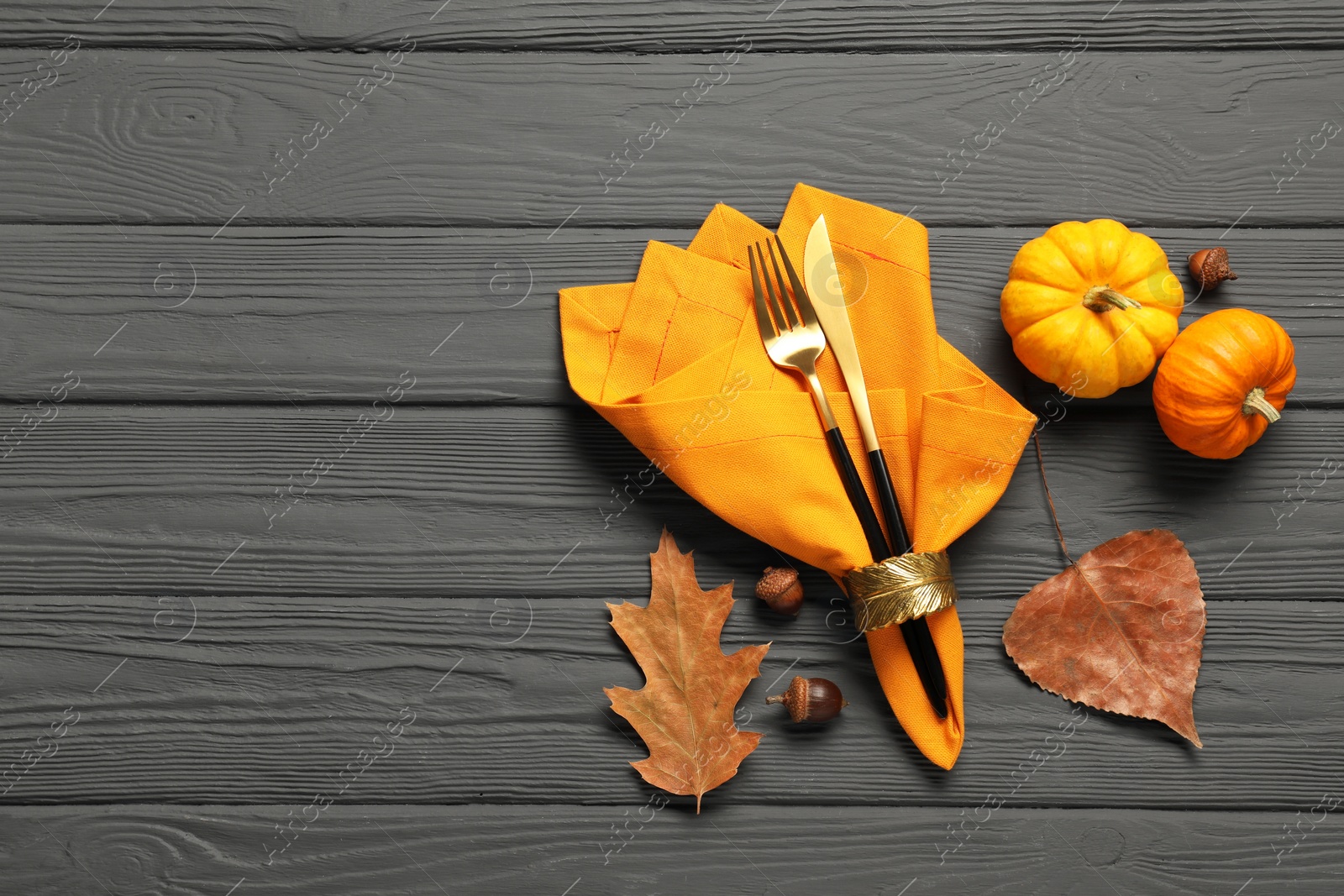 Photo of Cutlery, napkin and autumn decoration on gray wooden background, flat lay with space for text. Table setting