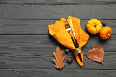 Photo of Cutlery, napkin and autumn decoration on gray wooden background, flat lay with space for text. Table setting