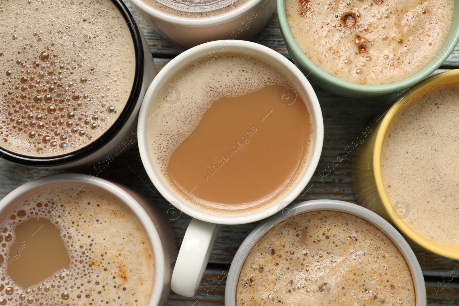 Photo of Many cups with different aromatic coffee on wooden table, flat lay