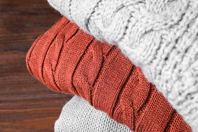 Image of Stack of folded warm sweaters on wooden background, closeup