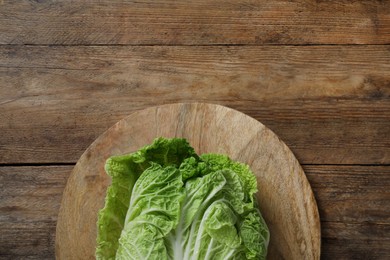 Photo of Cutting board with fresh ripe Chinese cabbage on wooden table, top view. Space for text