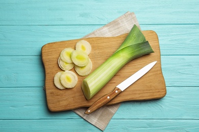 Fresh raw leek on light blue wooden table, flat lay. Ripe onion