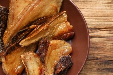 Photo of Tasty fried cracklings on wooden table, top view. Cooked pork lard