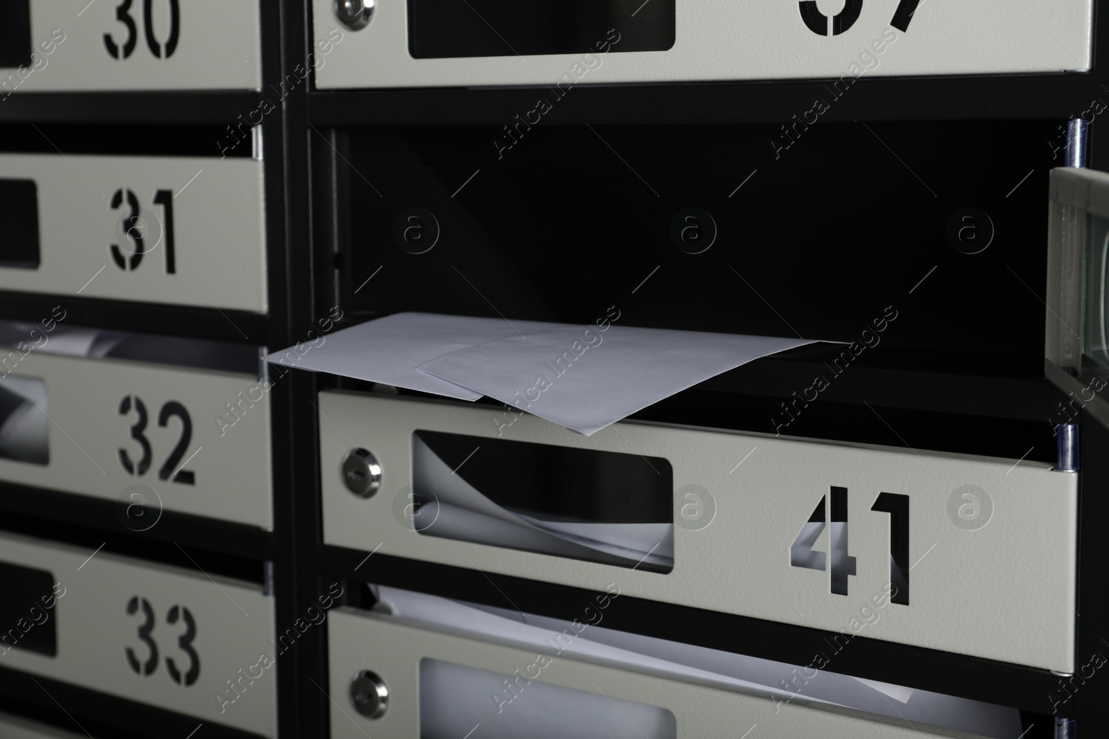 Photo of Open mailbox with keyhole, number and receipts, closeup