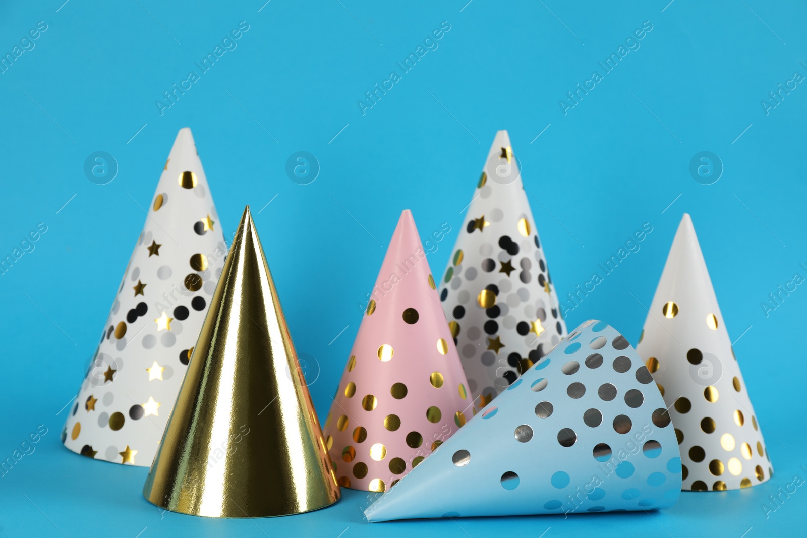 Photo of Bright party hats on light blue background