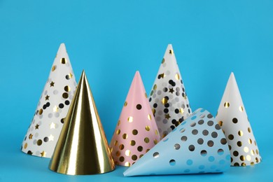 Photo of Bright party hats on light blue background