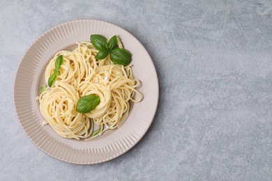 Delicious pasta with brie cheese and basil leaves on grey textured table, top view. Space for text