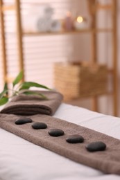 Photo of Towel with arranged spa stones on massage table in recreational center