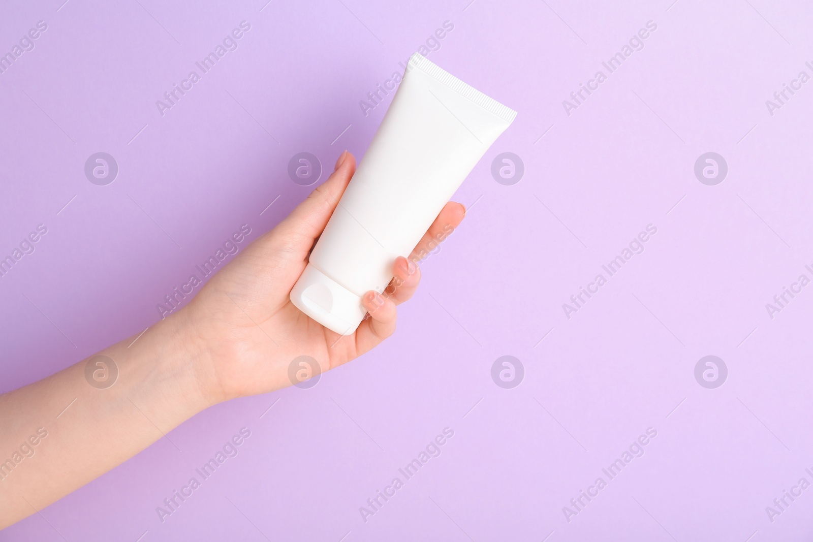 Photo of Woman with tube of cream on lilac background, closeup