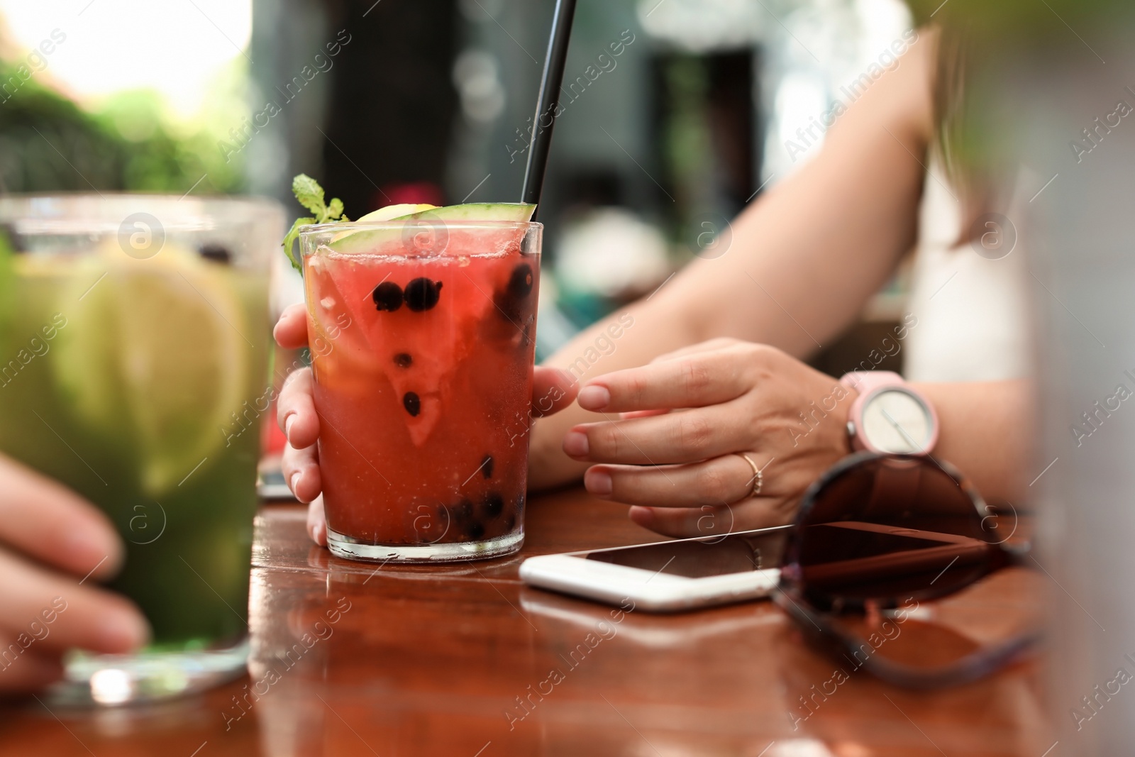 Photo of Women with glasses of tasty lemonade at table, closeup