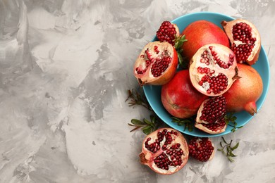 Delicious ripe pomegranates on grey table, flat lay. Space for text