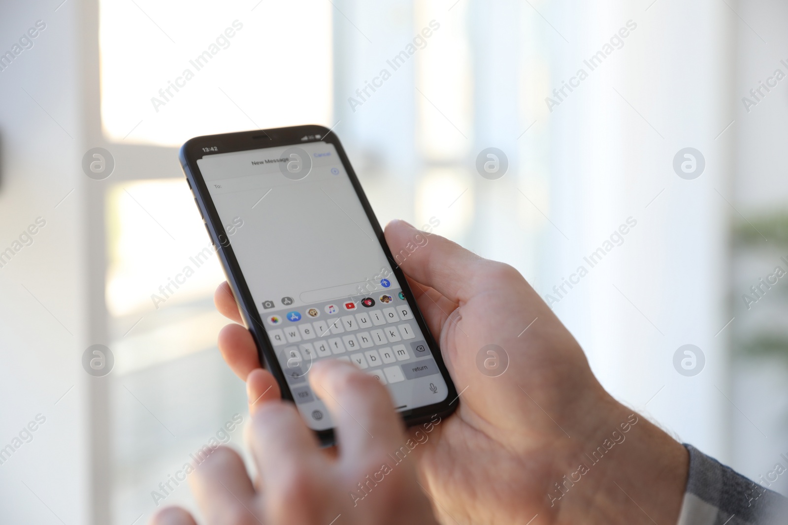 Photo of MYKOLAIV, UKRAINE - MARCH 16, 2020: Man typing message on iPhone 11 indoors, closeup