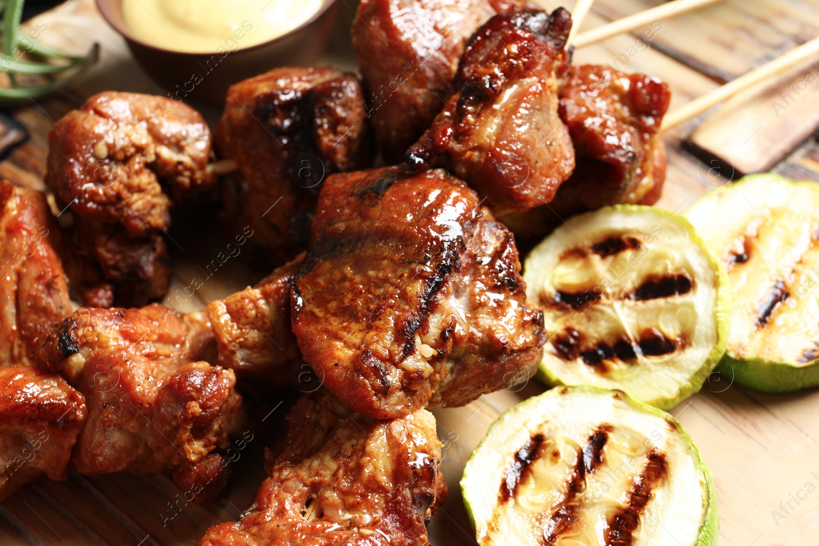 Photo of Delicious barbecued meat served with garnish on wooden background, closeup