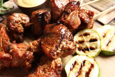 Photo of Delicious barbecued meat served with garnish on wooden background, closeup