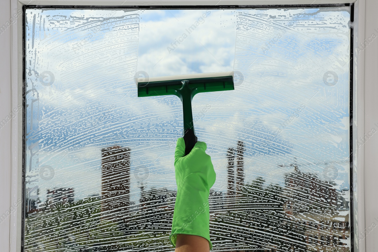 Photo of Woman cleaning glass with squeegee indoors, closeup