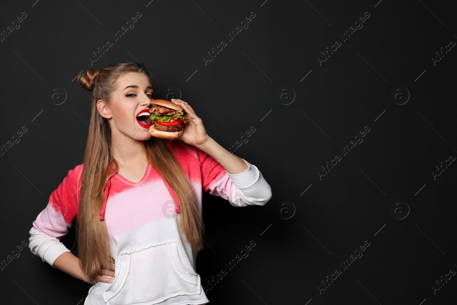 Photo of Pretty woman eating tasty burger on black background. Space for text