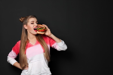 Photo of Pretty woman eating tasty burger on black background. Space for text