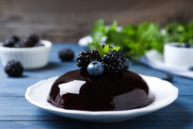 Photo of Delicious fresh jelly with berries on blue wooden table