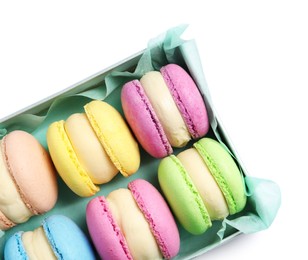 Many delicious colorful macarons in box on white background, top view